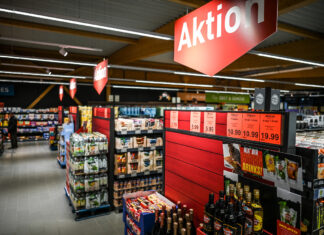 Ein Supermarkt hat eine Aktion mit Rabatten. Man sieht verschiedene Regale mit roten Schildern und vielen günstigen Produkten. Wer hier einkauft, kann bei der Aktion Geld sparen. Eine Traditionsmarke ist jetzt jedoch nicht wiederzuerkennen.