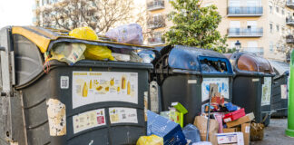 Überfüllte Mülltonnen in der Innenstadt mit Säcken und Müllbeuteln an der Seite. In den großen Tonnen sind zu viele Müllsäcke, die herausquellen. Das Wohngebiet hat wohl ein Problem mit der Entsorgung des Abfalls.