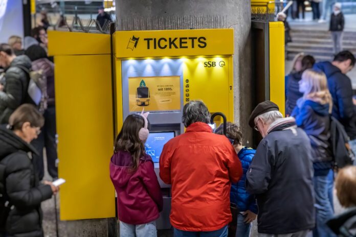 Mehrere Kunden stehen vor einem Ticketautomaten und kaufen sich ein Fahrticket