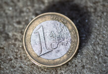 Eine 1-Euro-Münze auf dem Boden. Dieses alte Geldstück ist verschmutzt und ging schon durch viele Hände. Es handelt sich hierbei um Bargeld oder auch Hartgeld, das sehr oft den Besitzer wechselt.