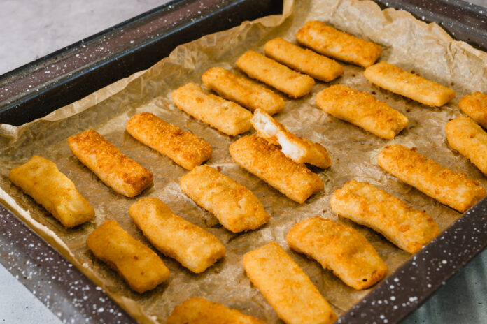 Fischstäbchen liegen auf einem Backblech mit Backpapier.