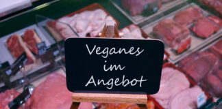 Eine Fleischtheke in einer Metzgerei mit einem Schild, das Veganes anbietet.