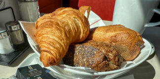 Auf einem Teller in einem Café oder Restaurant liegen verschiedene Lebensmittel für ein Frühstück. Das Frühstück besteht aus Croissants, Schokolade, Butter und Brötchen sowie Brot.