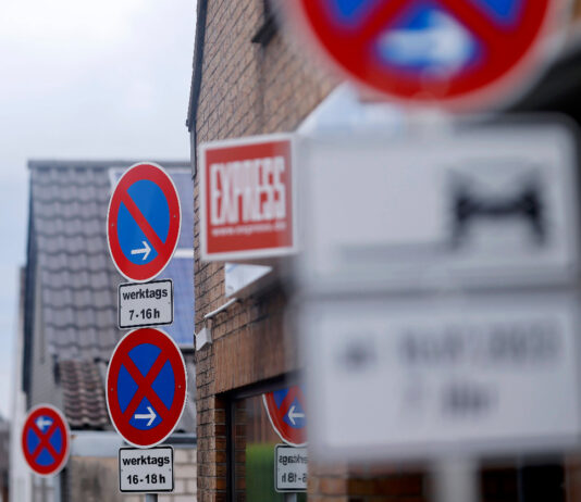 Mehrere Schilder mit Parkverboten an einer Straße, die teilweise verschwommen dargstellt sind und teilweise klar und deutlich zu erkennen sind.