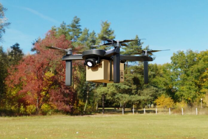Eine Drohne liefert fliegend ein Paket aus.
