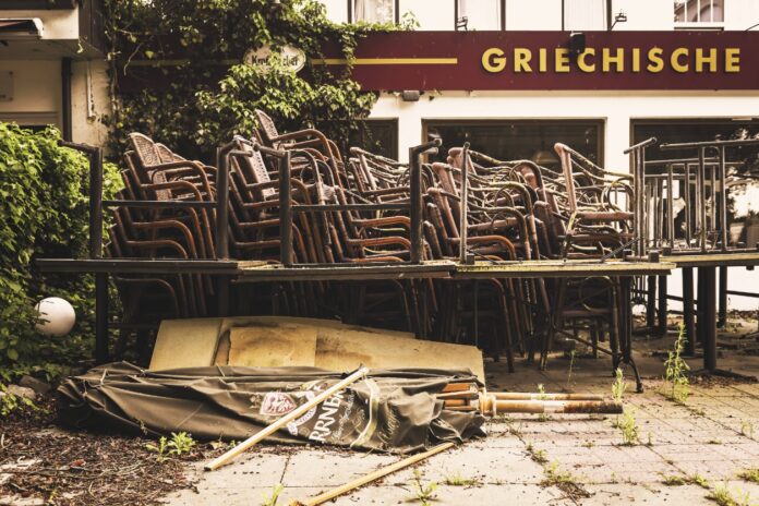 Ein ehemaliges griechisches Restaurant hat geschlossen vor der Tür stehen noch die auch gestapelten Terrassenstühle und Möbel