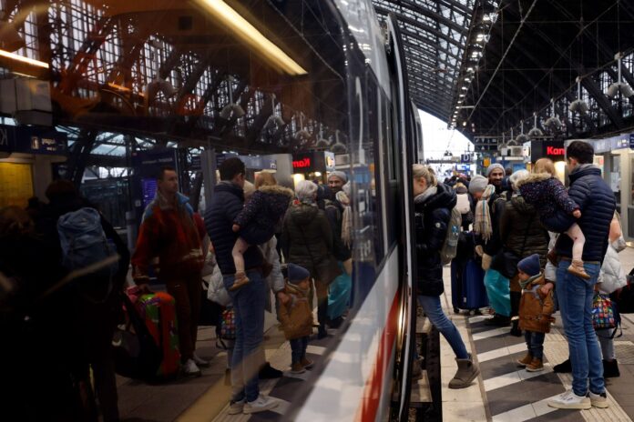 Viele Fahrgäste stehen am Bahnsteig und warten auf den ankommenden Zug