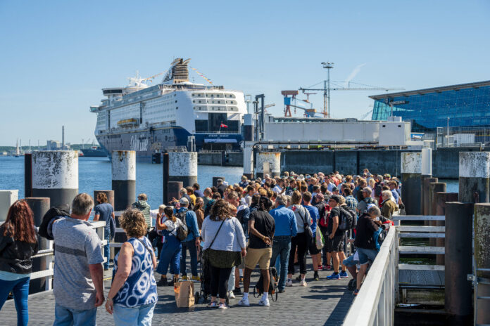 Viele Passagiere machen sich auf einem Steg auf den Weg zu einem Luxusdampfer.