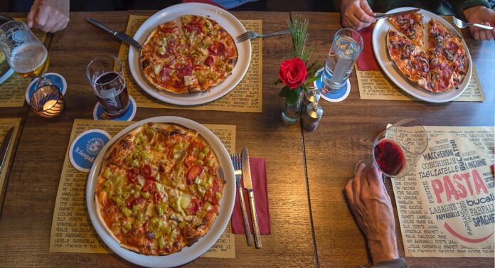 Auf einem gedeckten Tisch im Restaurant stehen drei Pizzen.