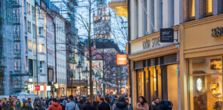 Menschen beim Einkaufen. Die Bürger laufen durch die Einkaufspassage an den Läden und Geschäften vorbei. Sie schauen durch die Verkaufsfenster hinein, einige Kunden gehen in ein Geschäft, um Produkte zu kaufen.