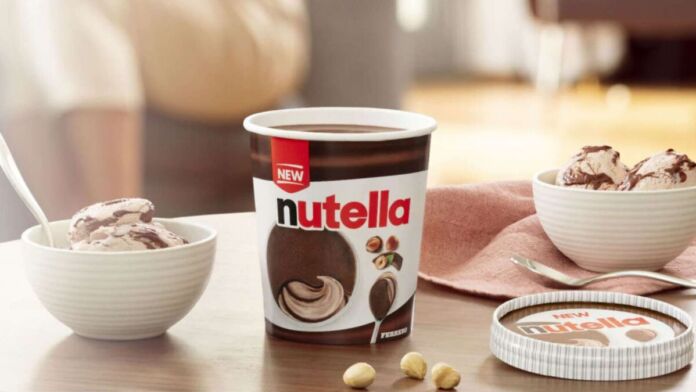 Eine neue Eiskreation der Marke Nutella steht auf einem Tisch neben Haselnüssen. Es ist eine Haselnuss- und Kakao-Eiscreme mit gefrorenen Nutellaschichten.