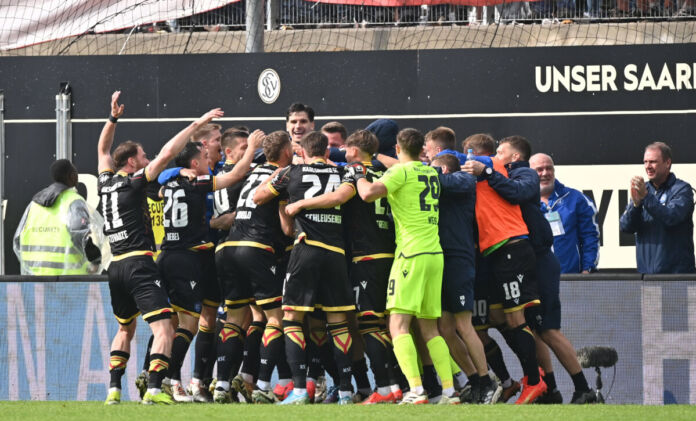 Die Spieler des KSC umarmen sich. Die Mannschaft des Karlsruher SC spielt gemeinsam auf dem Rasen während eines Spiels in der zweiten Bundesliga.