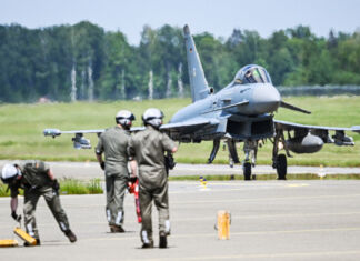 Drei Soldaten der Bundewehr auf einem Landeplatz für Kampfjets. Im Hintergrund steht ein Eurofighter. Die Armee führt auf der abgelegenen Startbahn Übungen durch.