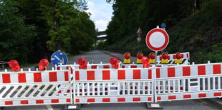 Eine Absperrung mit einem Durchfahrt-Verboten-Schild stehen mitten auf einer Straße. Die ländlich gelegene Straße ist gesperrt, weil es zu einem Erdrutsch kam.