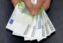 Die Hand einer Frau hält fünf grüne hundert Euro Scheine in der Hand. Mit dem Bargeld sollen hohe Gebühren bezahlt werden.