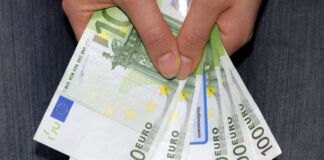 Die Hand einer Frau hält fünf grüne hundert Euro Scheine in der Hand. Mit dem Bargeld sollen hohe Gebühren bezahlt werden.