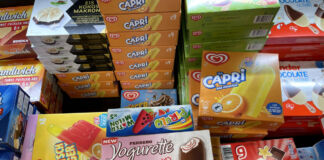 In der Auslage eines Supermarkts liegen aufeinander und nebeneinander gestapelte Eissorten verschiedener Hersteller. Yogurette, Capri, Cola Rocket und die Eiswaffel und viele mehr sind dabei.