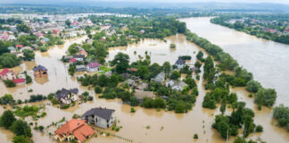 Aus der Luftperspektive sieht man, dass ein ganzes Gebiet überflutet worden ist. Ganze Landstriche sind von den Wassermassen bedeckt. Wege und Straßen sind nicht mehr passierbar.