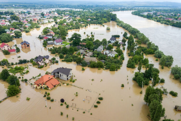 Aus der Luftperspektive sieht man, dass ein ganzes Gebiet überflutet worden ist. Ganze Landstriche sind von den Wassermassen bedeckt. Wege und Straßen sind nicht mehr passierbar.