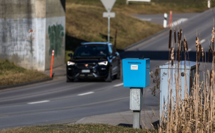 Ein Auto fährt auf einer Straße durch eine Unterführung. Vorne ist ein blauer Kasten mit der Aufschrift Verkehrszählung zu sehen.