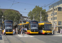 Die Straßenbahnen fahren durch die Innenstadt am Bahnhofsvorplatz vorbei. Passanten und Fahrgäste gehen vorbei, steigen ein und aus und nutzen das öffentliche Verkehrsmittel.