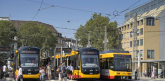 Die Straßenbahnen fahren durch die Innenstadt am Bahnhofsvorplatz vorbei. Passanten und Fahrgäste gehen vorbei, steigen ein und aus und nutzen das öffentliche Verkehrsmittel.