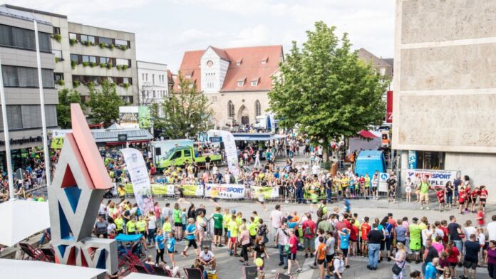 Viele Läufer nehmen an einem Volks- oder Stadtlauf teil. Die Strecke führt durch die Innenstadt. Sie laufen an Streckenposten und Zuschauern vorbei.