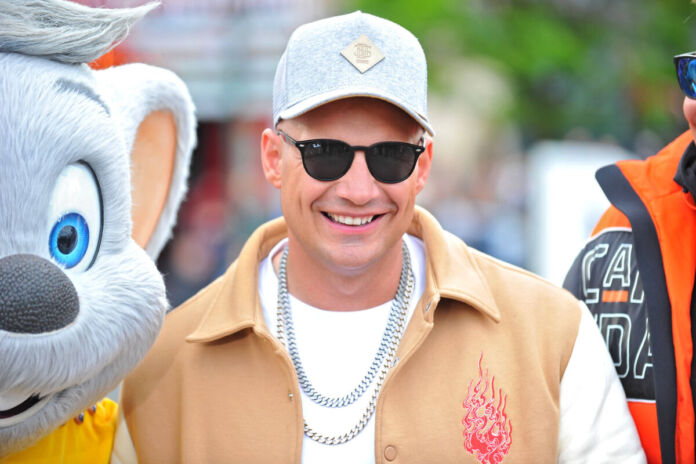 Pietro Lombardi, der Sänger und DSDS Juror steht neben einer großen Stofftier Maus. Er trägt eine Sonnenbrille, eine Mütze und zwei dicke, silberne Ketten.