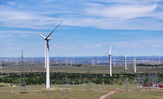 Ein großer XL-Windpark in freier Natur. In diesem Park stehen viele Windräder, die aus der Kraft des Windes Energie für die Haushalte erzeugen.