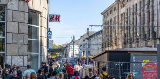 In der Karlsruher Innenstadt tummeln sich zahlreiche Menschen an einem verkaufsoffenen Sonntag. Im Hintergrund stehen gelbe Sonnenschirme, die offensichtlich zu einem Lokal gehören und die Vorbeigehenden zum Verweilen einladen.
