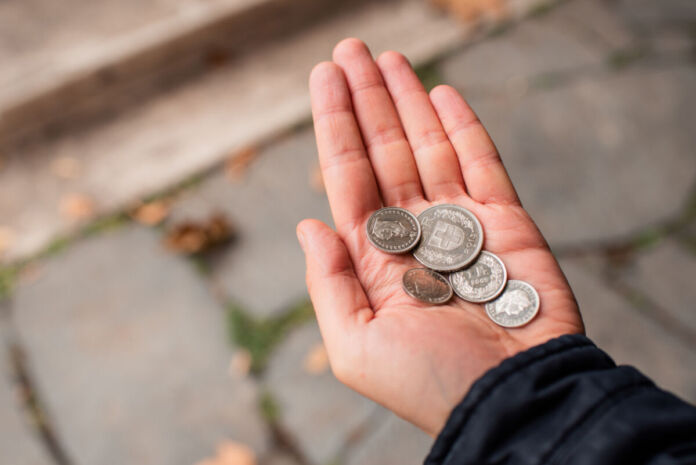 Eine Person hält verschiedene Geldstücke mit Bargeld in der Hand. Diese Münzen gelten als Zahlungsmittel, es handelt sich um Münzen unterschiedlichen Wertes. Die Münzen haben eine ausländische Währung.