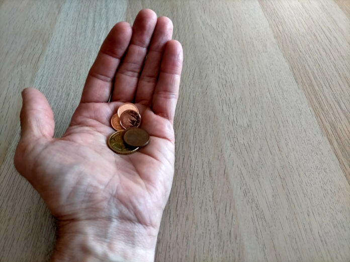 In der offenen linken Hand eines europäischen Mannes liegen vereinzelte Geldstücke. Es sind ein 20-Cent-Stück, ein 2-Cent-Stück sowie einige 1-Cent-Münzen.