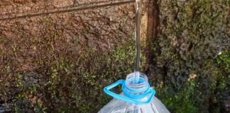 Das Leitungswasser oder Regenwasser läuft in eine große Plastikflasche. In der Flasche wird es gesammelt. Es bildet einen Wasservorrat für eine bestehende Knappheit.