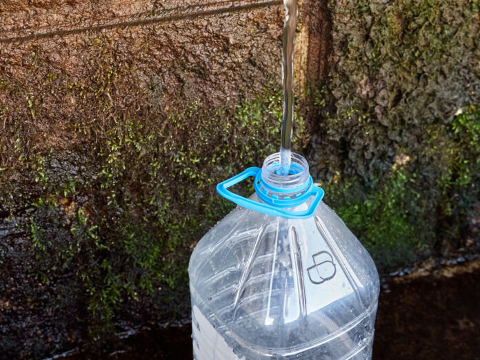 Das Leitungswasser oder Regenwasser läuft in eine große Plastikflasche. In der Flasche wird es gesammelt. Es bildet einen Wasservorrat für eine bestehende Knappheit.