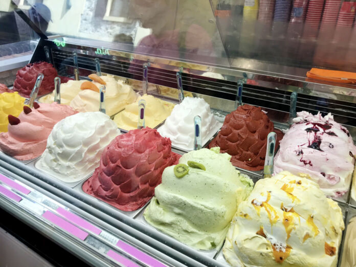 Eine Truhe in einer Eisdiele ist mit vielen verschiedenen Sorten Speiseeis gefüllt. Es gibt Schoko, Vanille und Erdbeereis in dem Eiscafé. Das Eis ist eine tolle Erfrischung im Sommer.