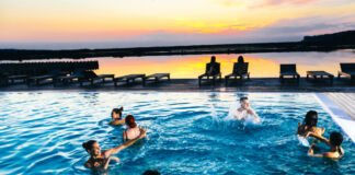 Verschiedene Menschen schwimmen mitten in der Nacht in einem Schwimmbad oder in einem Swimmingpool gemeinsam. Sie planschen und haben Spaß im Wasser.