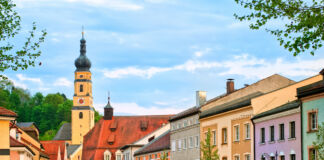 Viele bunte, alte Häuser sowie eine Kirche stehen im Zentrum einer kleinen Stadt. Der Ort ist ein schönes Ausflugsziel für Touristen. Besucher kennen die Straße, denn sie ist sehr berühmt.