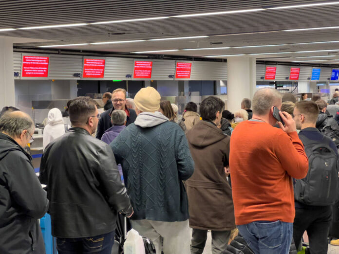 Am Schalter des Flughafens sind viele Menschen und Passagiere. Sie stehen Schlange, es herrscht Unordnung und Chaos. Wahrscheinlich versuchen Sie, Ihren Flug noch rechtzeitig zu erreichen.