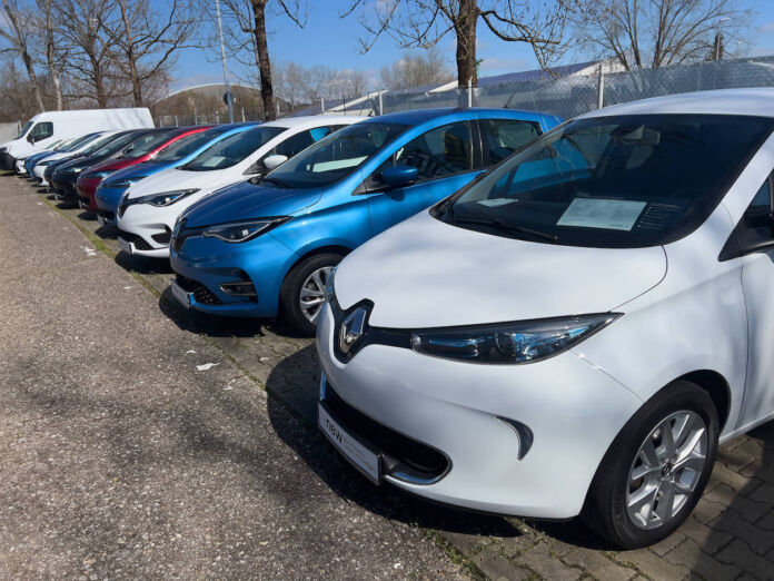 Mehrere Kleinwagen der Marke Renault stehen in einer Reihe nebeneinander auf einem Parkplatz. Es handelt sich um gebrauchte E-Autos, die zum Verkauf angeboten werden.