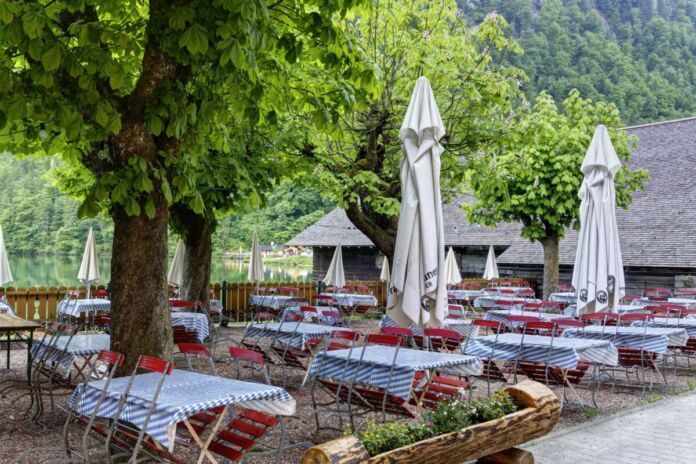 Ein Biergarten ist völlig leer. Im Restaurant sind keine Gäste mehr, es hat wohl geschlossen. Die Terrasse wirkt verwaist, es liegen aber noch Tischdecken auf den Tischen.