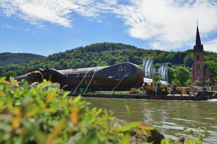 Ein altes, ausgemustertes U-Boot wird über einen Fluss transportiert. Das Boot ist eine echte Attraktion und soll in einem Museum ausgestellt werden.