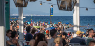Mehrere Urlauber feiern gemeinsam am Strand. Viele Touristen sind am Meer, um zu baden und Urlaub zu machen. Die Strandpromenade ist ebenso überfüllt