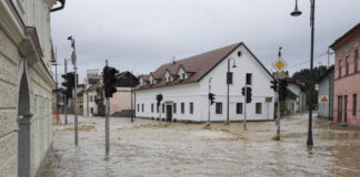 In einer kleinen Stadt ist ein Hochwasserereignis passiert. Die ganze Ortschaft steht unter Wasser und die Straßen und Zugänge zu den Häusern sind durch das bräunliche Wasser unpassierbar.