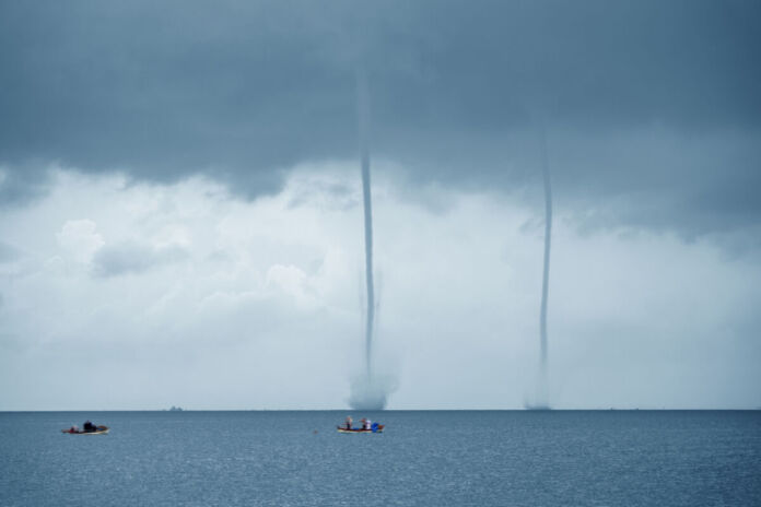 Zwei Windhosen sind auf dem Meer unterwegs. Es sind kleine Tornados, die eine große Gefahr darstellen. Solche Wetterphänomene treten im Zuge des Klimawandels immer häufiger auf.