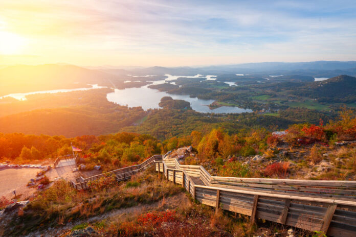 Eine weite Landschaft erstreckt sich am Horizont während der Abenddämmerung. Eine Treppe geht einen Hügel hinauf. Es ist ein schöner weiter Blick in die Natur, auf Wälder und Seen.