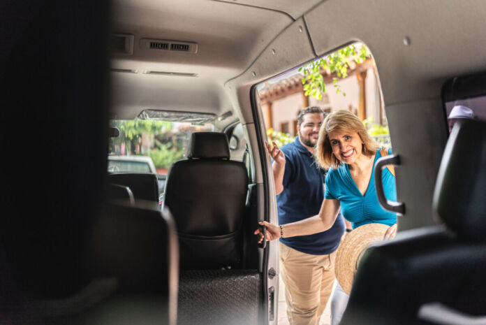 Das Wageninnere eines kleinen Reisebusses. Eine südländische Frau mittleren Alters ist aufgeregt und steigt in den Bus. Draußen ist schönes Wetter wie im Sommerurlaub.