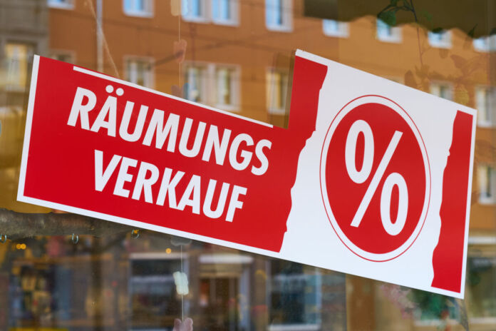 Im Schaufenster eines Geschäftes ist ein Schild angebracht, auf dem "Räumungsverkauf" in Weiß auf rotem Hintergrund steht. Daneben ist ein Prozentzeichen abgebildet. Offensichtlich schließt das Geschäft bald.