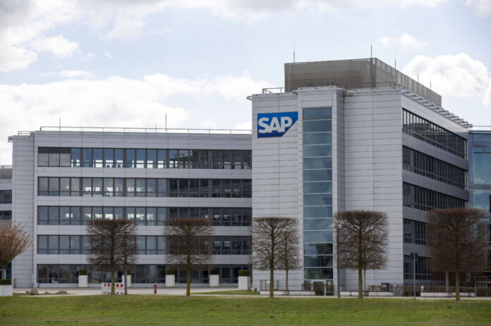 Auf dem Bild ist ein modernes Bürogebäude zu sehen, das die Firmenzentrale der SAP darstellt. Das Gebäude hat eine helle Fassade und viele Fenster. Auf der rechten Seite des Gebäudes ist das große, blau-weiße SAP-Logo gut sichtbar.