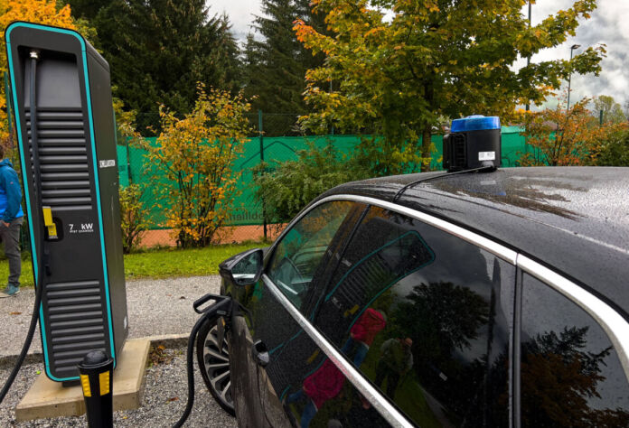 Ein Elektroauto der Polizei steht an einer Ladestation und wird aufgeladen. Auf dem Dach des Polizei-Autos befinden sich ein Blaulicht und eine Sirene.