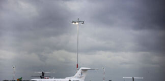 Ein Flugzeug steht startbereit auf dem Flughafen. Um das Flugzeug herum sind die Fluggäste, die an Bord gehen, das Sicherheitspersonal und die Stewards.